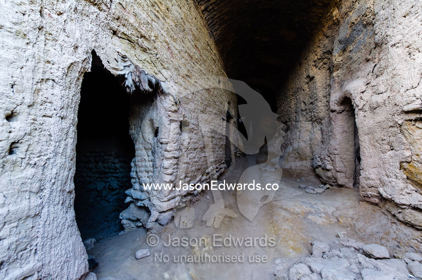 A laneway passes between buildings of crumbling handmade brick in the ruins of an ancient abandoned village in the desert. Kharanagh, Yazd, Yazd Province, Islamic Republic of Iran.
