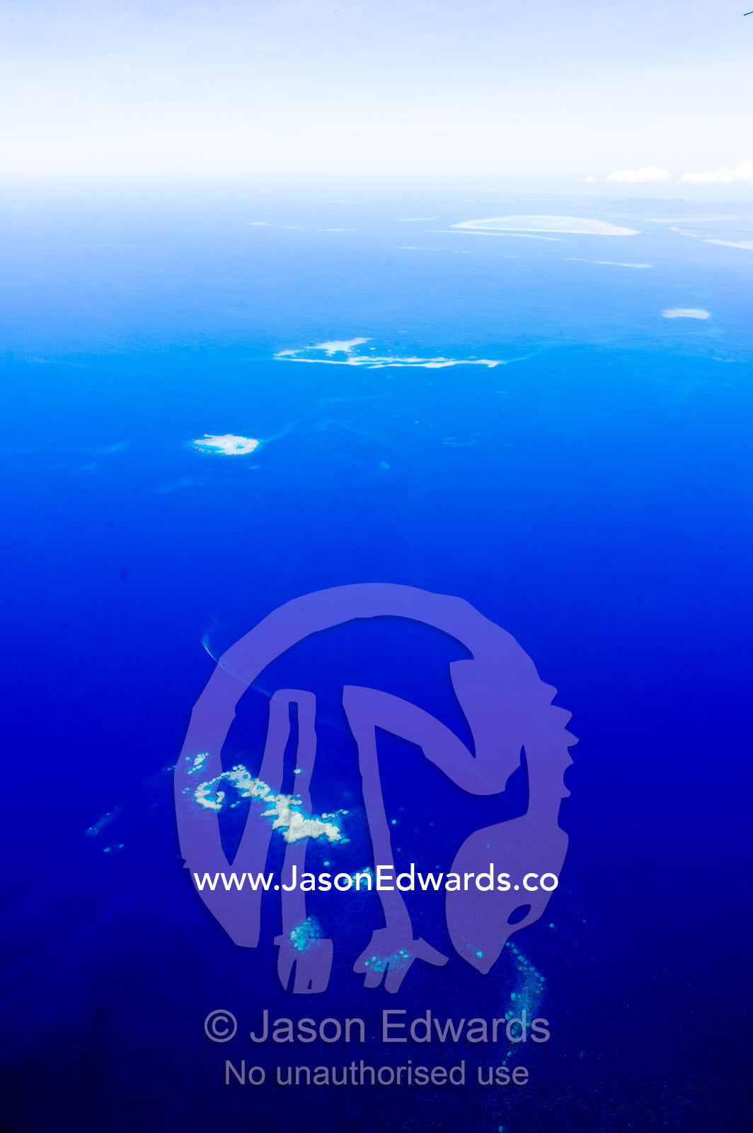 Clouds floating over a deep blue tropical ocean with isolated sandbars. Taveuni Island, Somosomo Strait, Pacific Ocean, Fiji Islands.