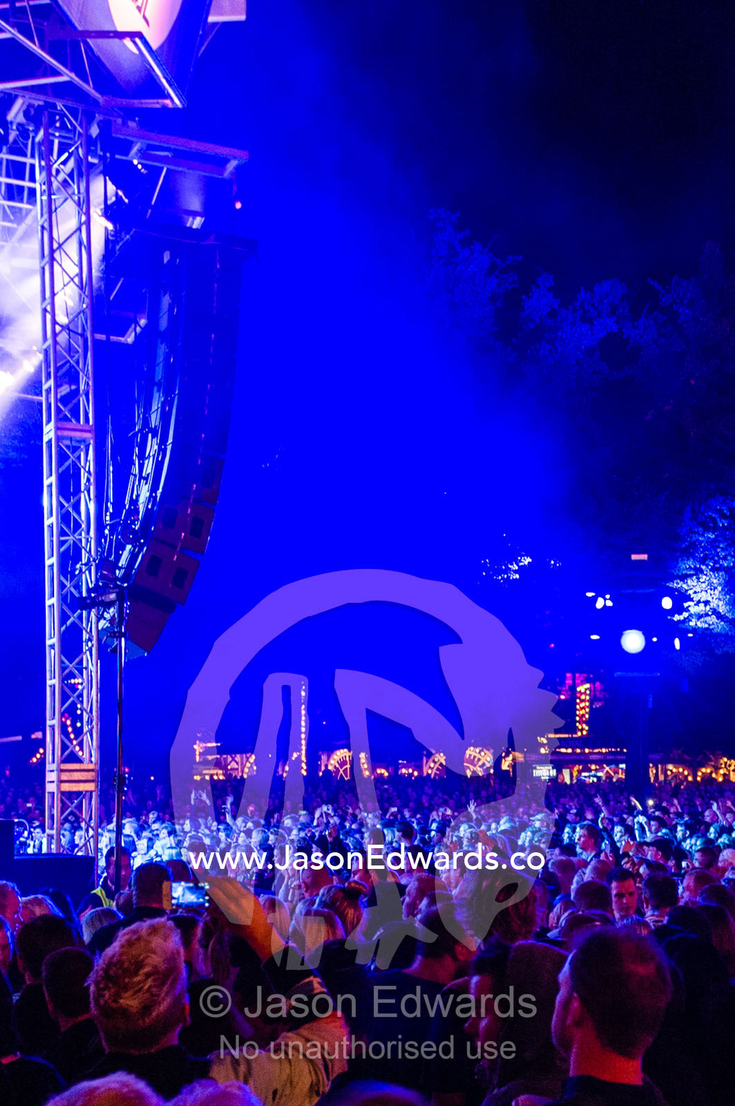 An enormous crowd watching a concert illuminated by neon blue lights. Tivoli Gardens, Copenhagen, Denmark.