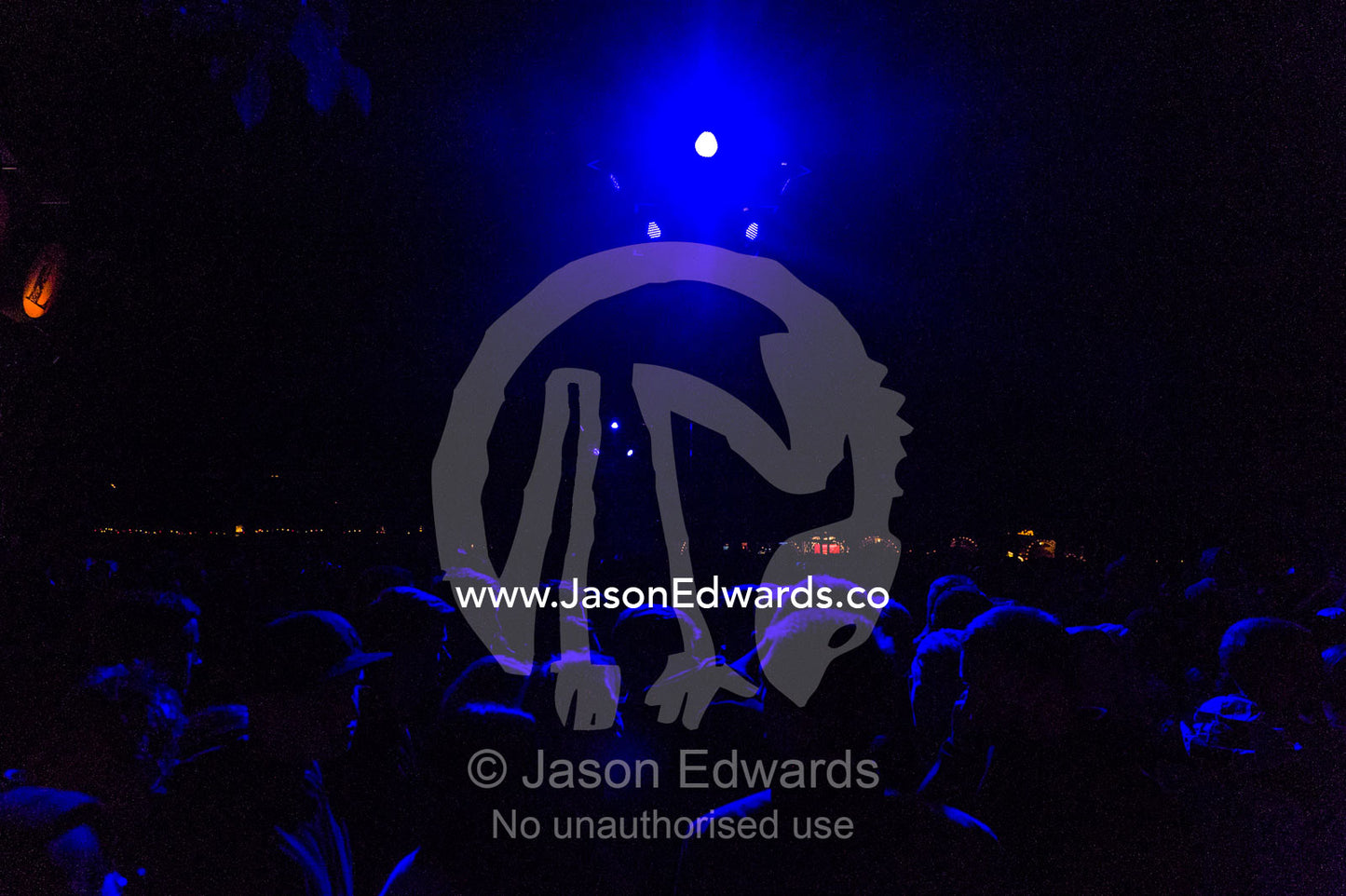 The heads of people in a crowd watching a concert illuminated by neon blue lights. Tivoli Gardens, Copenhagen, Denmark.