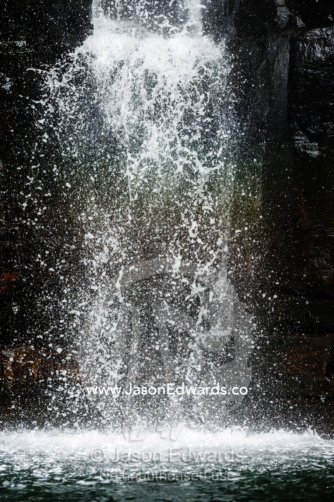 A waterfall cascades down a sheer sandstone cliff covered in cyanobacteria. King George River, King George Falls, Kimberley Coast, Western Australia, Australia.