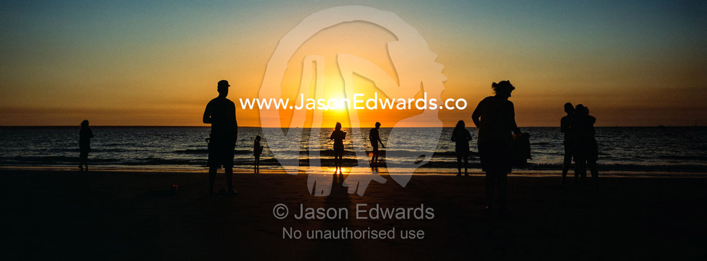 The silhouette of families and tourists watching the setting sun from Mindil Beach in Darwin. Mindil Beach Sunset Markets, Darwin, Northern Territory, Australia.