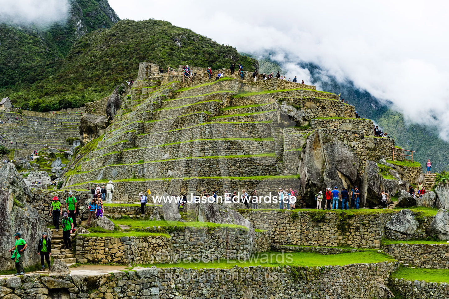 Tourists explore the Inca stone terrace ruins at Macchu Picchu. Peru.