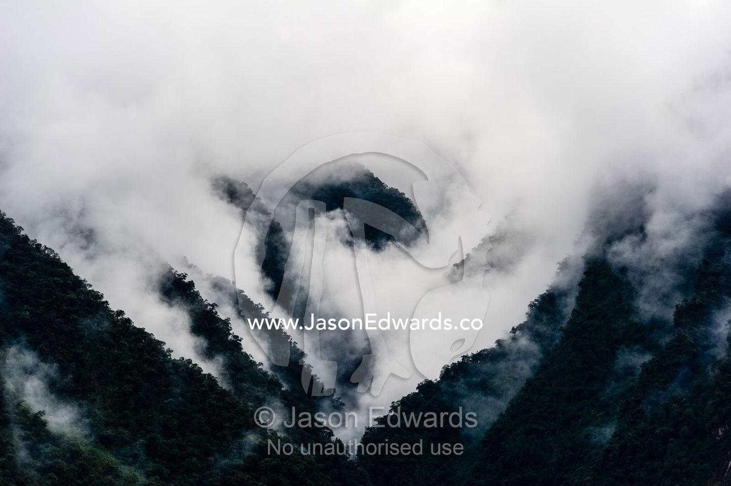 Storm clouds engulf the steep forested slopes and jagged mountain peaks of the Andes. Peru.