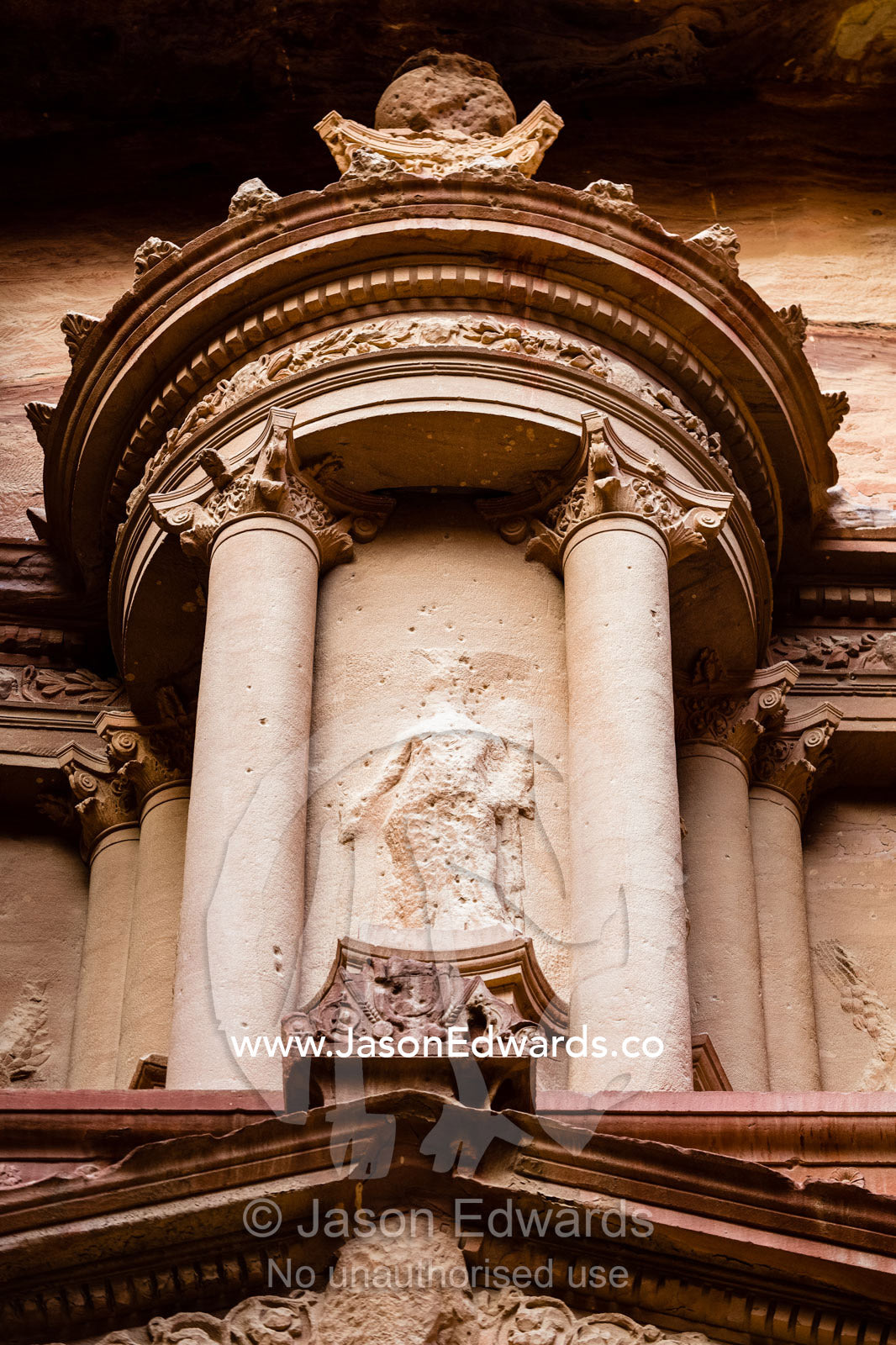 Detail of rock-cut facade of The Treasury tomb showing the circular tholos with eroded relief sculpture of the goddess Isis, Al-Uzza. Petra, The Lost City of Petra, Jordan