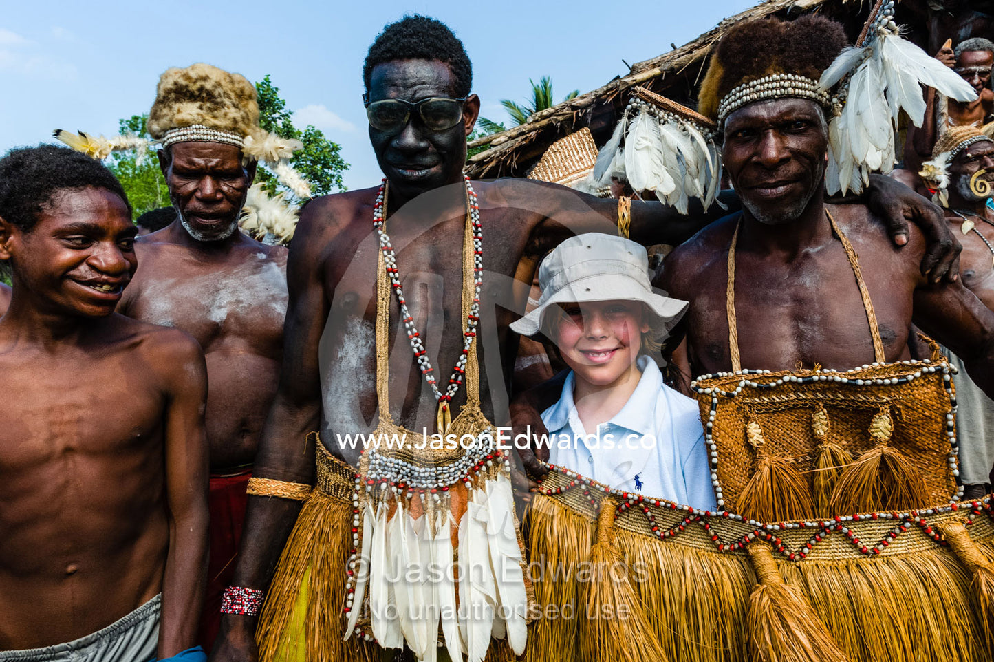 A western boy meets Asmat warriors in grass skirts during a tribal ceremony. Yahunyufri Village, Asmat Regency, Papua, Indonesia