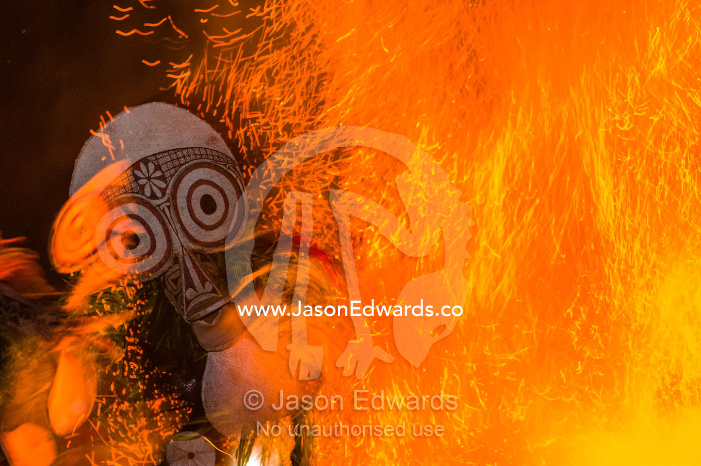 Baining warriors wearing grass and reed outfits and giant duck-like masks taunt the flames and their gods during a tribal fire ceremony. Rabaul, New Britain, Papua New Guinea