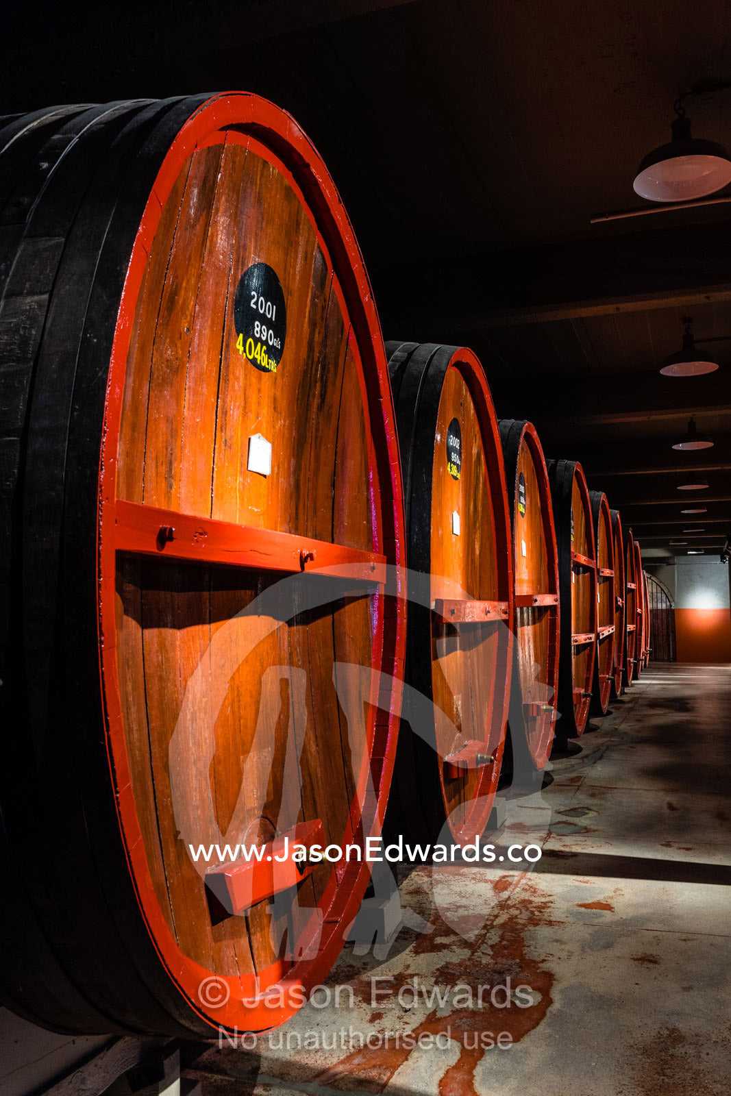 A row of wine barrels and vats stored in a climate controlled underground tunnel. Rosslyn Park, Adelaide, South Australia, Australia