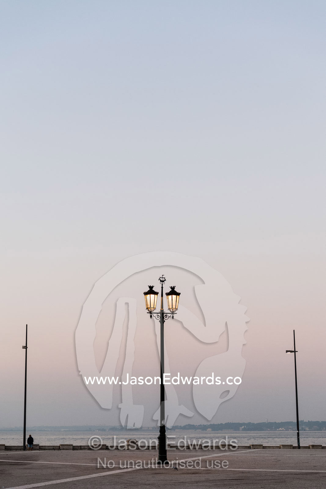 An ornate antique street lamp glowing in the pastel pre-dawn light. Lisbon, Lisboa, Portugal