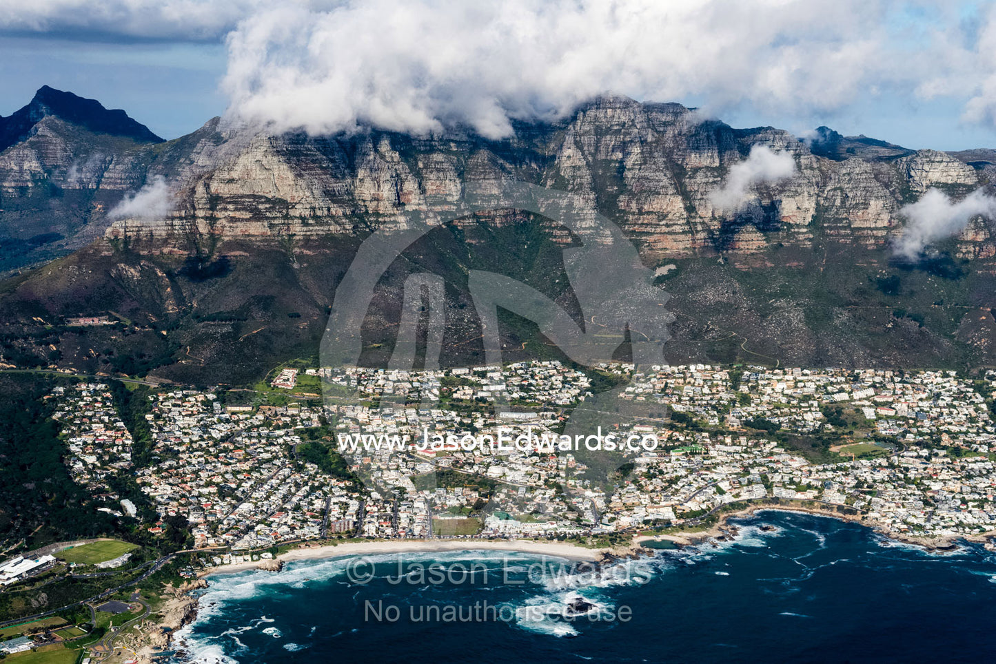 An aerial view of sprawling suburbs along a rugged mountainous coastline. Cape Point National Park, South Africa
