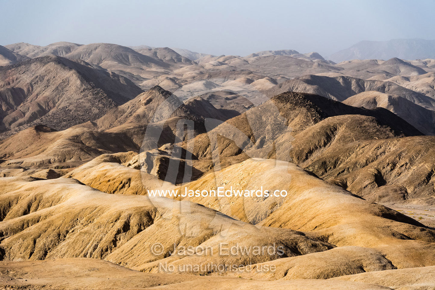 Barren mountains baking in the afternoon heat roll across the desert. Namib Desert, Namib-Naukluft National Park, Namibia