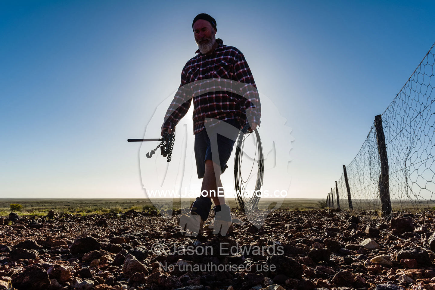 A patrol officer repairs the Dingo Fence or Dog Fence, a pest-exclusion fence built to keep dingoes away from sheep flocks. Coober Pedy, Dingo Fence, Dog Fence, South Australia, Australia