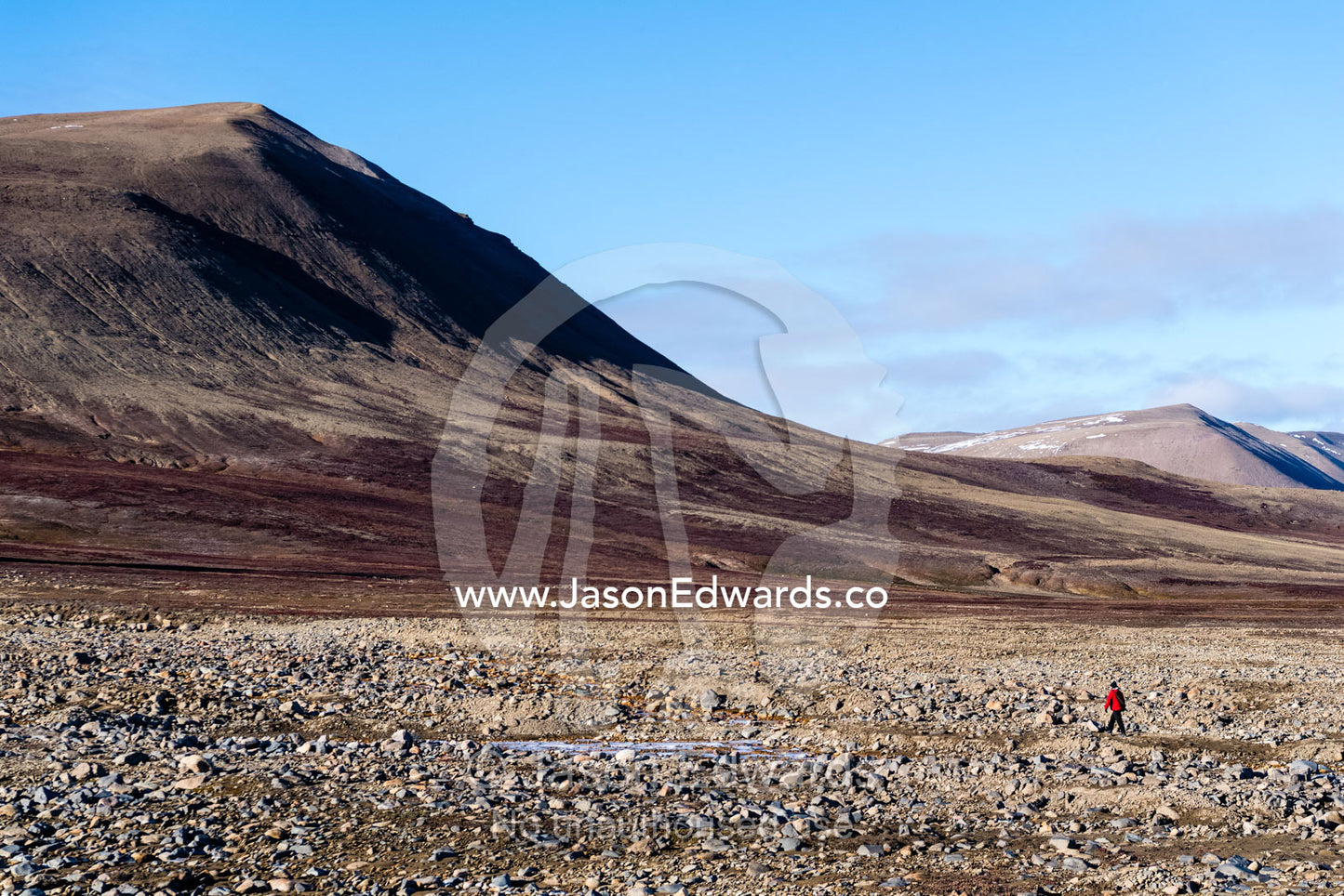A solitary hiker explores a boulder plain in an arctic tundra valley. Scoresby Sound, Constable Point, Greenland