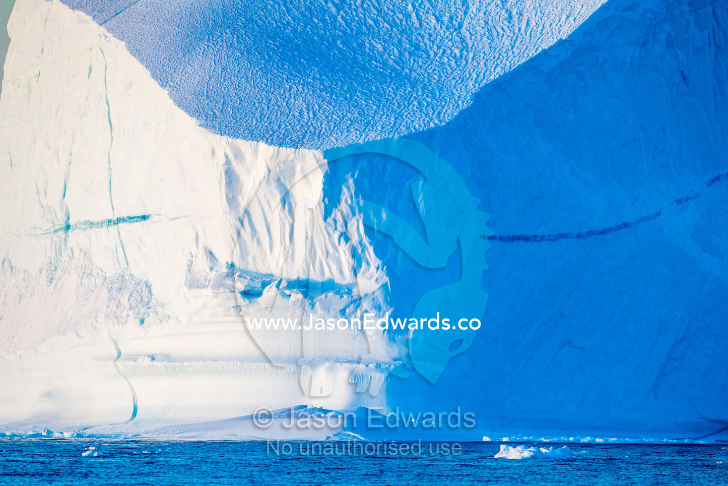 Late afternoon light falls across the surface of sheer iceberg cliffs floating in the arctic. Milne Land, Hall Bredning Fjord, Scoresby Sound, Greenland