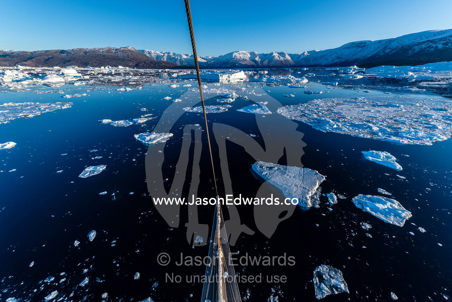 A Tall Ship Schooner navigating between icebergs near a glacier fracture zone. Rolinge Glacier, Rode Fjord, Scoresby Sound, Greenland