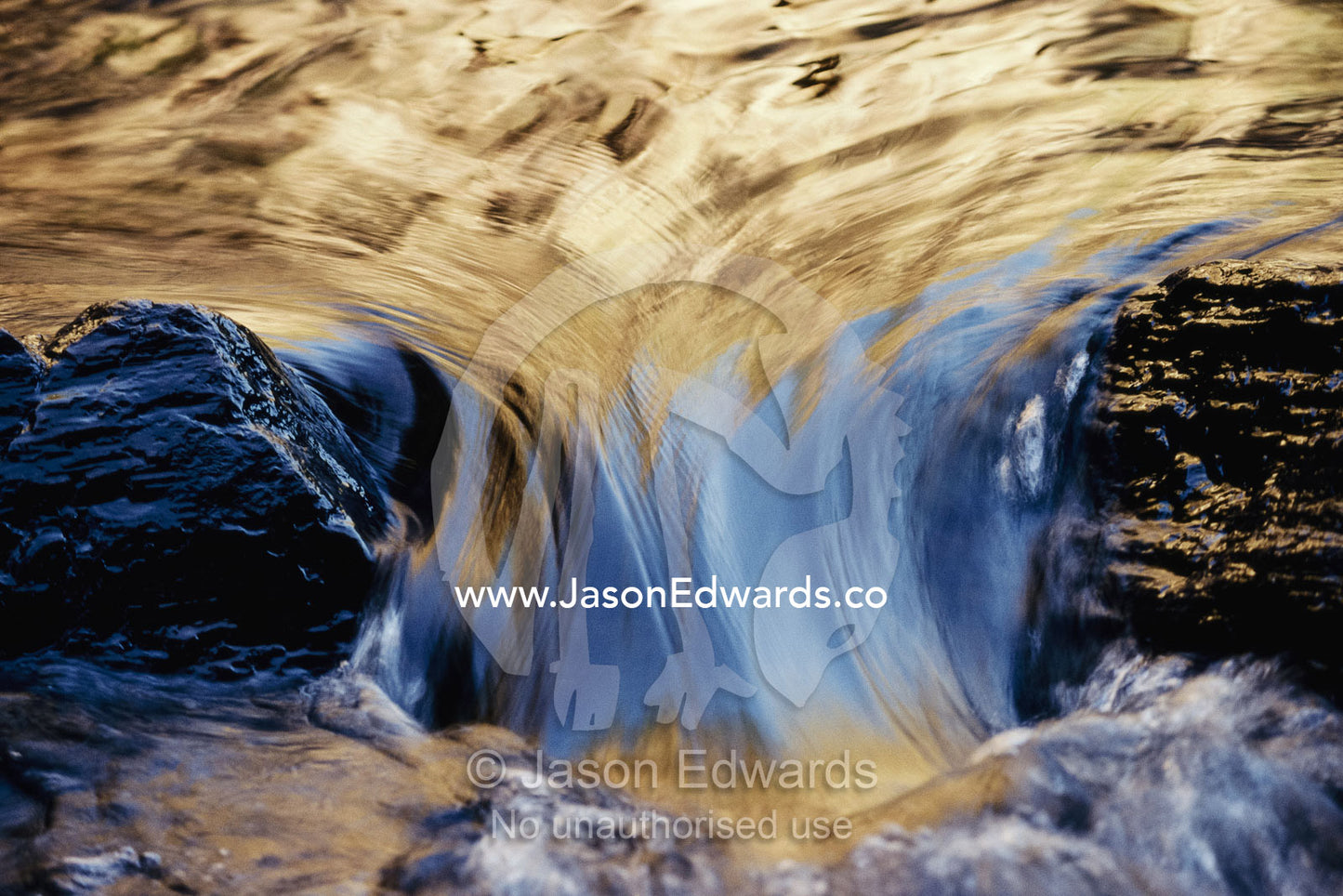 Light reflected on water flowing over rocks. Litchfield National Park, Northern Territory, Australia.