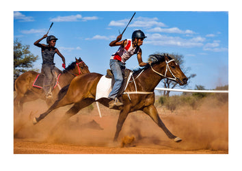 Race horses gallop down the straight on a red sand track in the outback. Ntaria, Hermannsburg, Northern Territory, Australia.