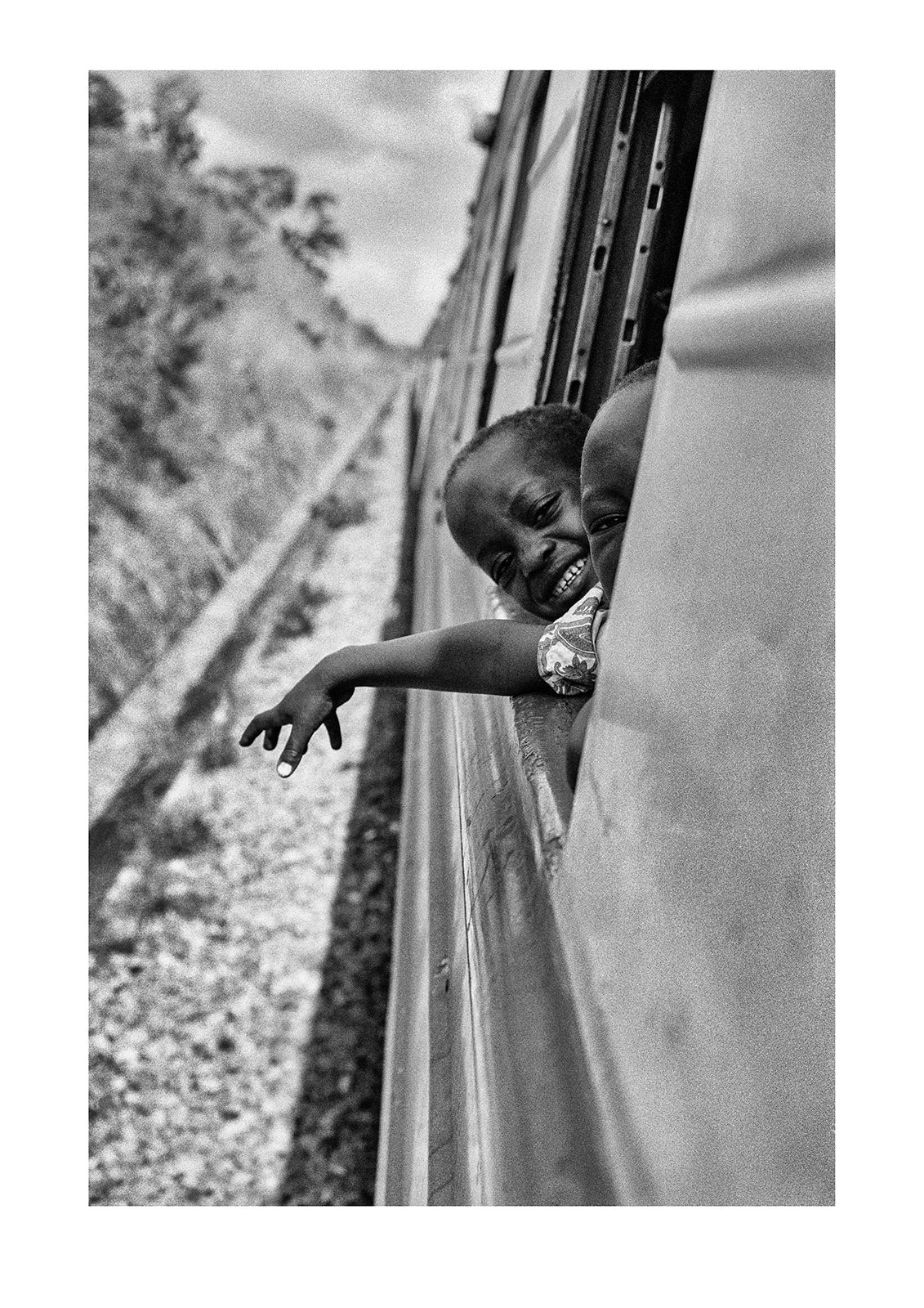 Young, curious boys looking from a train as it crosses the remote heart of Zambia. Captured on Ilford HP5 black and white negative film. The Blue Train, Zambia.