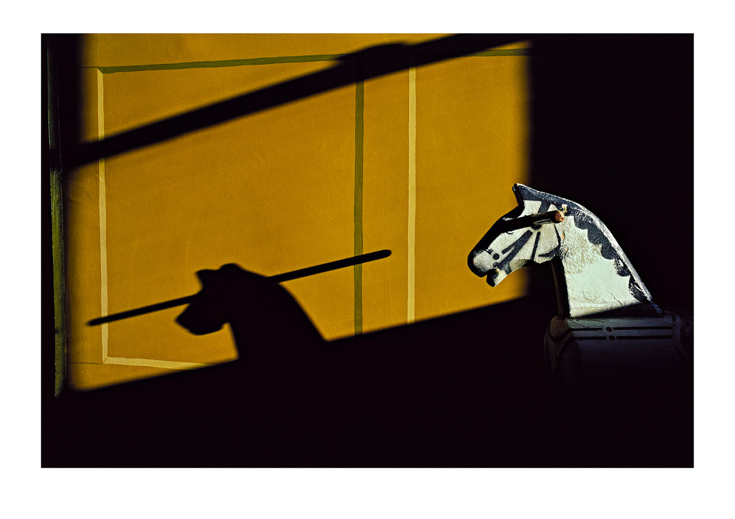 The late day sun casts a shadow of a rocking horse onto a wall. Tasmania, Australia.