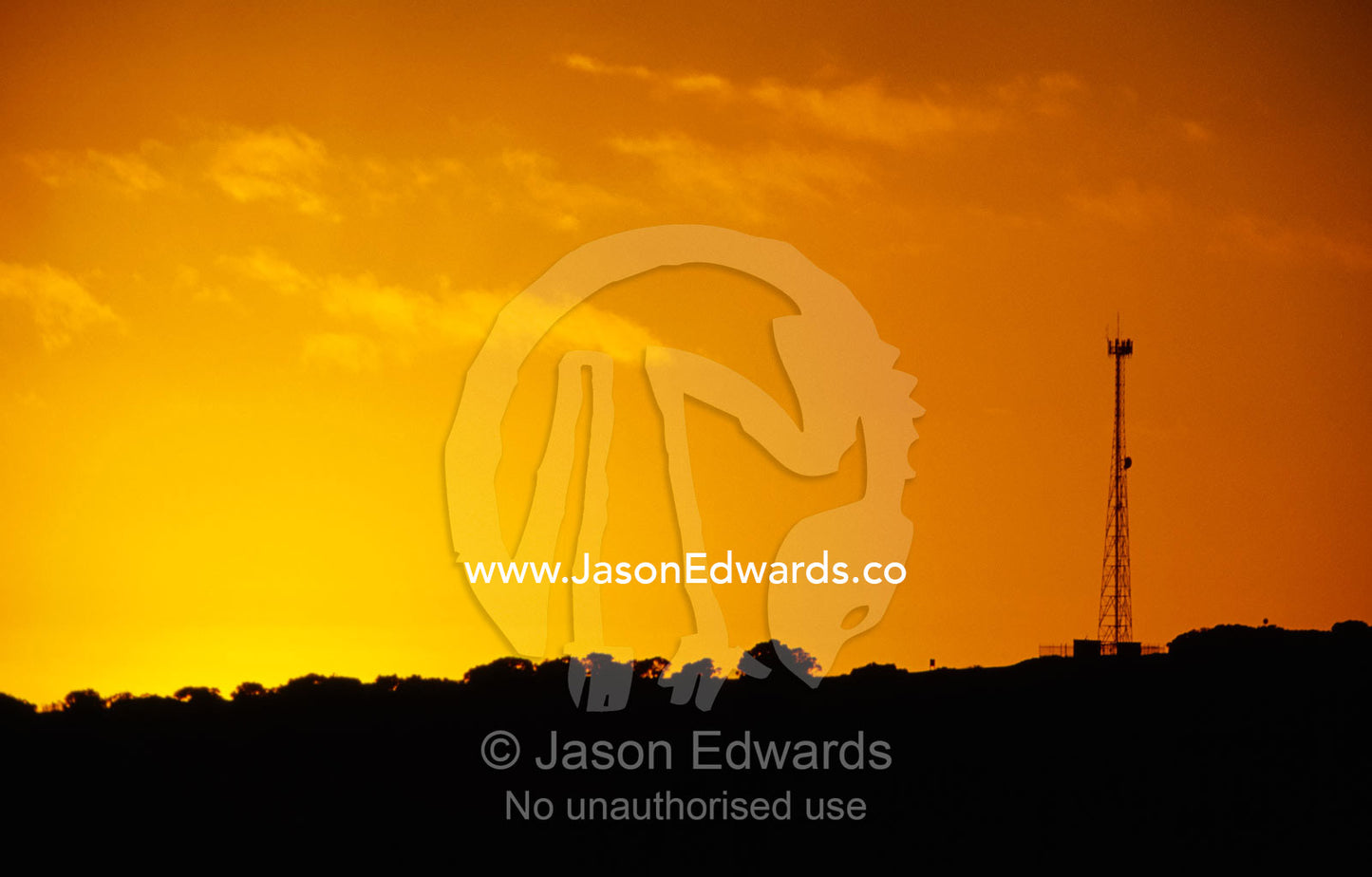 A radio antenna silhouetted against an orange sky at sunrise. Coorong National Park, South Australia.