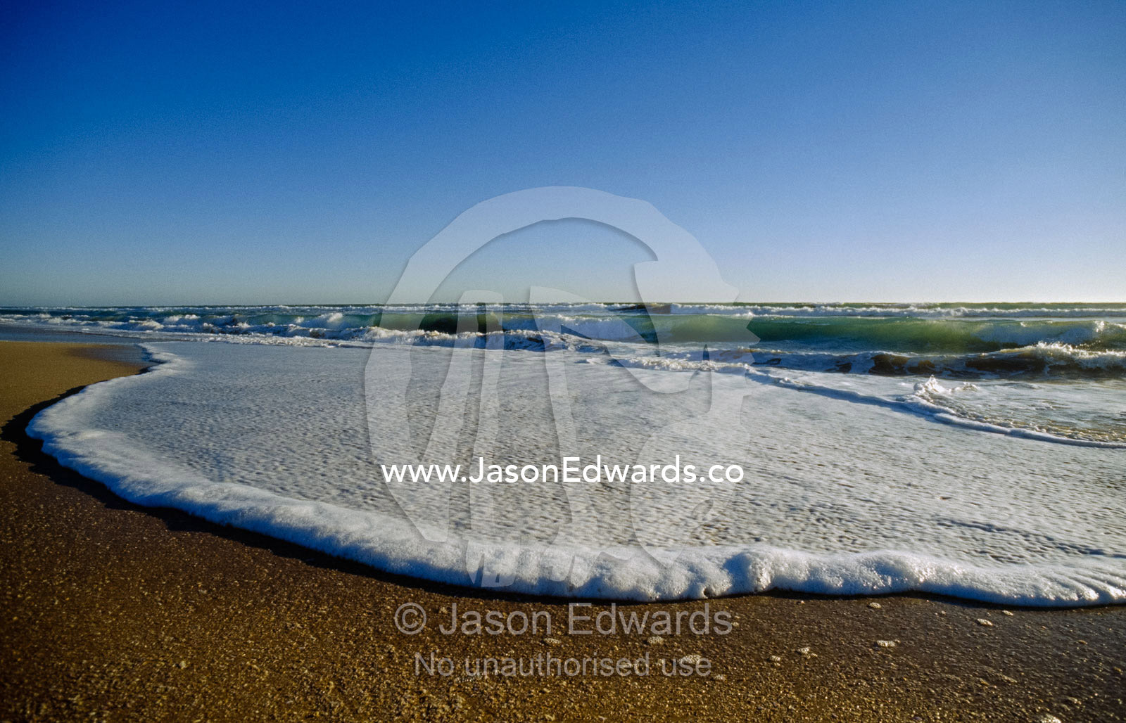 Crashing waves spread foam across a sandy beach. Coorong National Park, Younghusband Penninsula, South Australia.