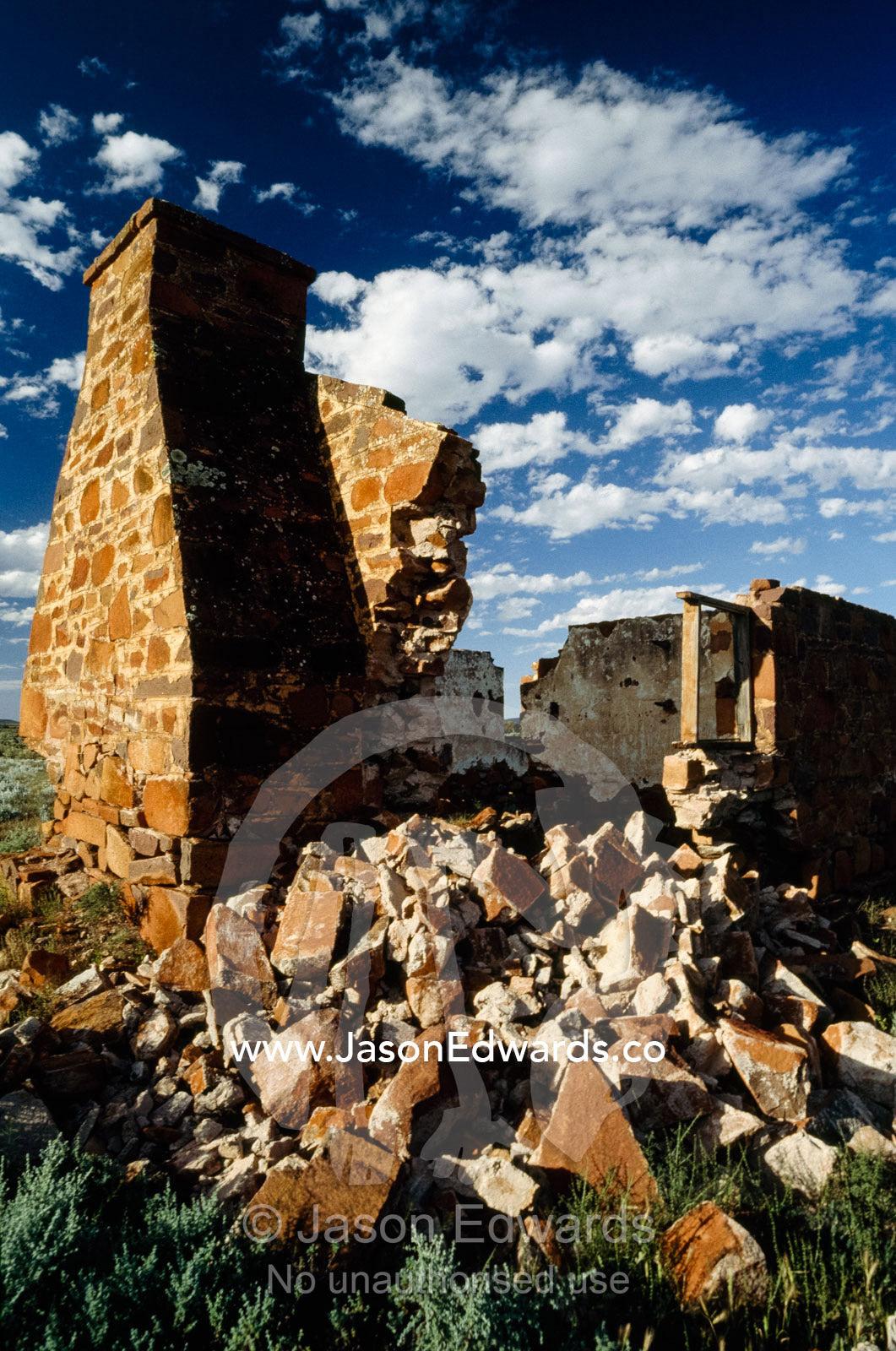 The ruins of an outback homestead under a cloud-filled blue sky. Pondanna Station, South Australia.