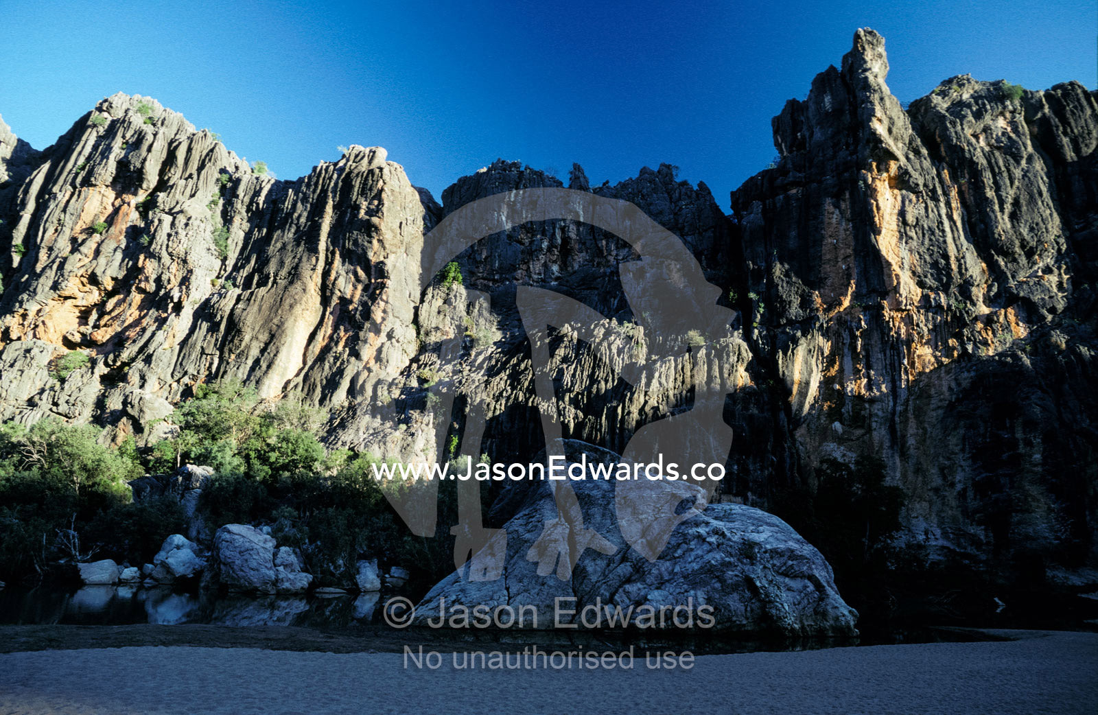 Shadows fall across limestone walls of an inland desert gorge rockpool Lennard River Kimberley Ranges Western Australia.
