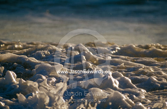 Foaming waves break onto a remote and rugged beach at sunset. Coorong National Park, Younghusband Penninsula, South Australia.