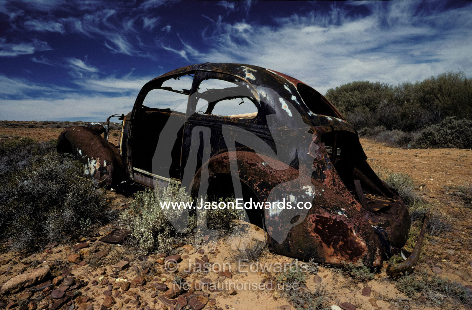 Burnt out antique car wreck discarded to rust away in the desert. Andamooka, South Australia.