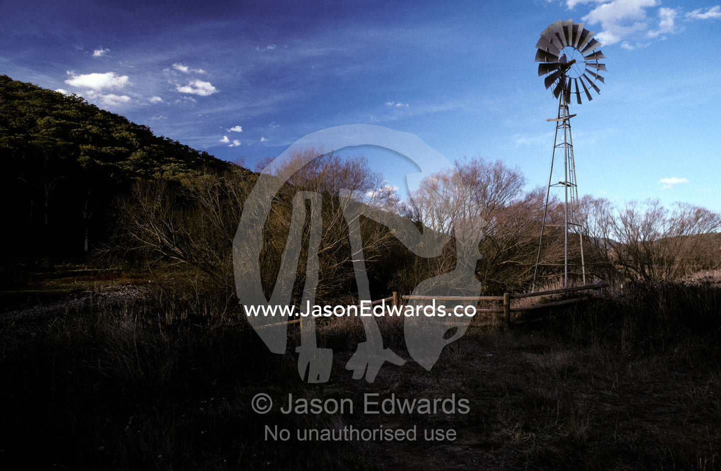 A windmill situated alongside a river in a field in late winter. Howqua River, Victoria Australia