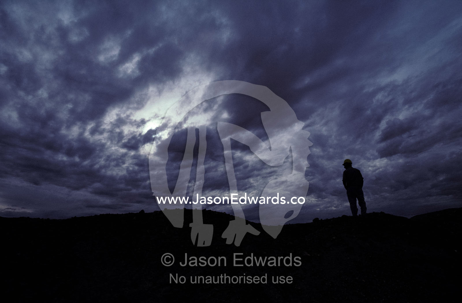 Silhouette of opal miner standing on slurry heap with storm clouds. Coober Peedy, South Australia.