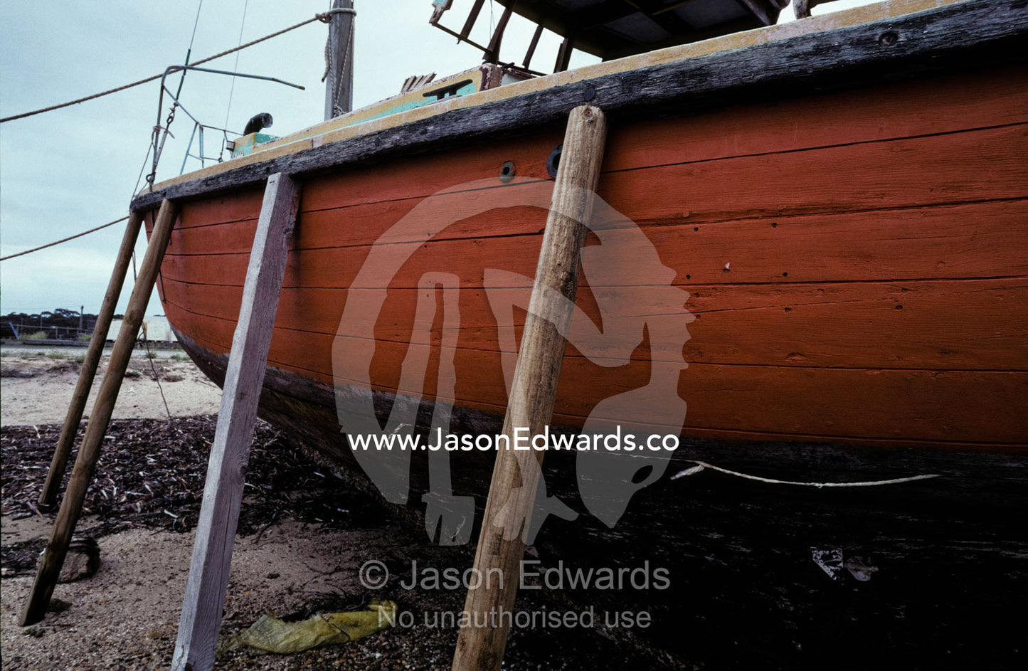 An old fishing boat beached at low tide on stilts for repairs. Kangaroo Island, American River, South Australia.