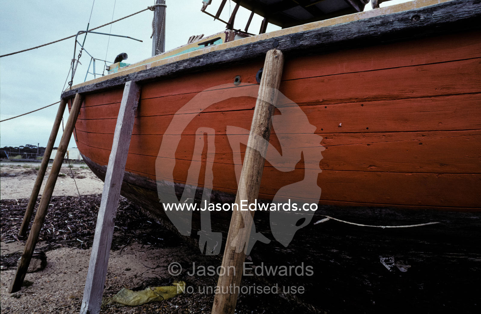 An old fishing boat beached at low tide on stilts for repairs. Kangaroo Island, American River, South Australia.