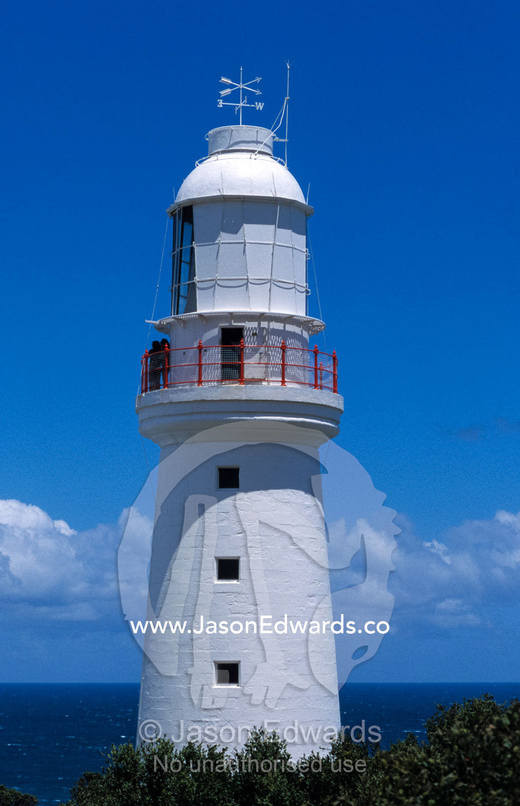 The 1848 Cape Otway Lighthouse overlooks a calm sea beneath a blue sky Cape Otway National Park, Victoria Australia.