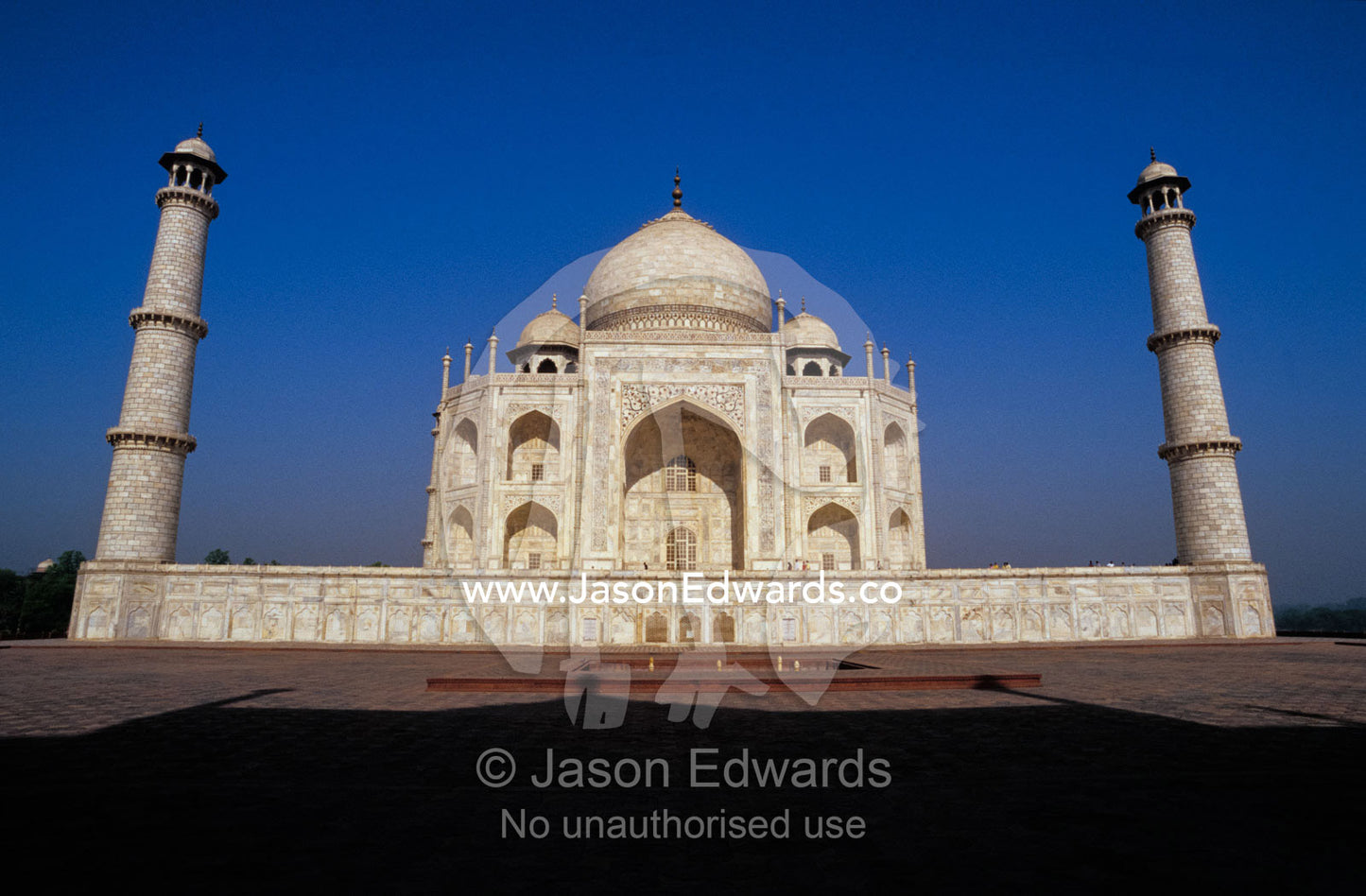 The Taj Mahal and two minarets at dawn against a clear blue sky. Agra, India.