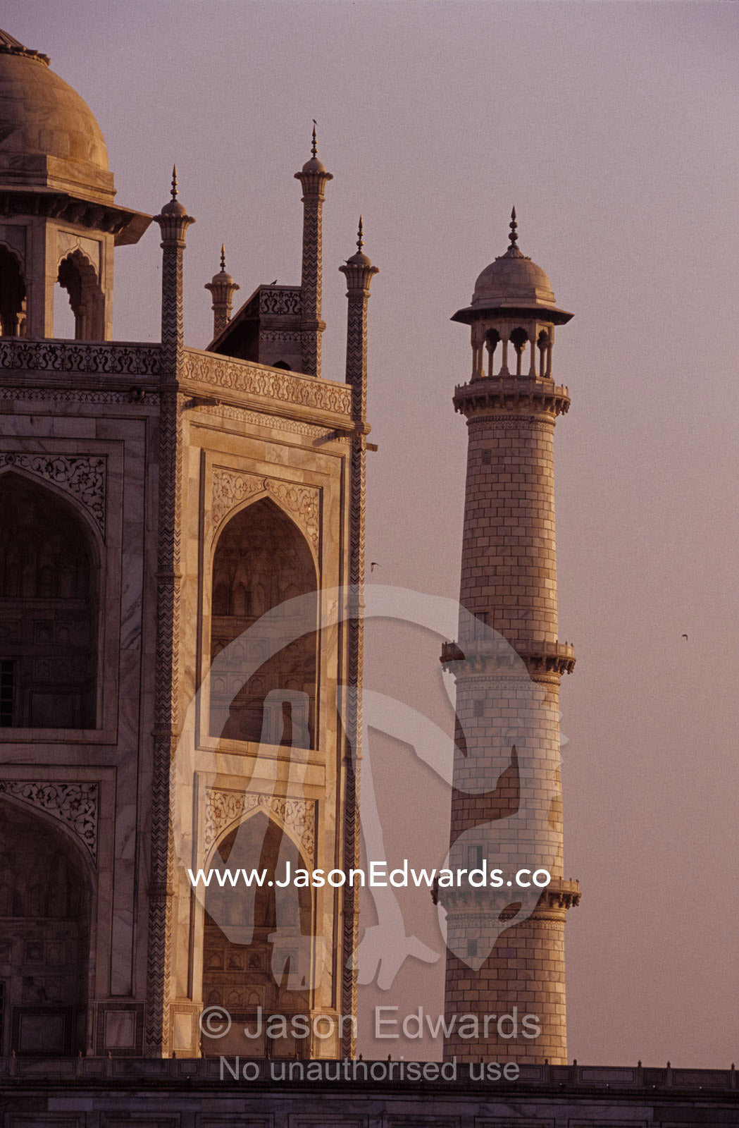 The Taj Mahal and one of it's  massive marble minarets at dawn. Agra, India.