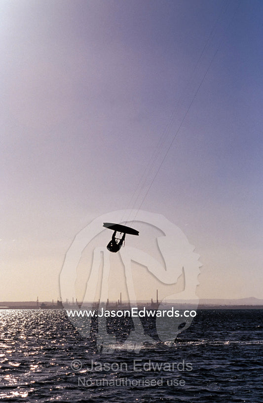 The silhouette of a person kite surfing, in a choppy windswept bay. Point Henry, Victoria, Australia.