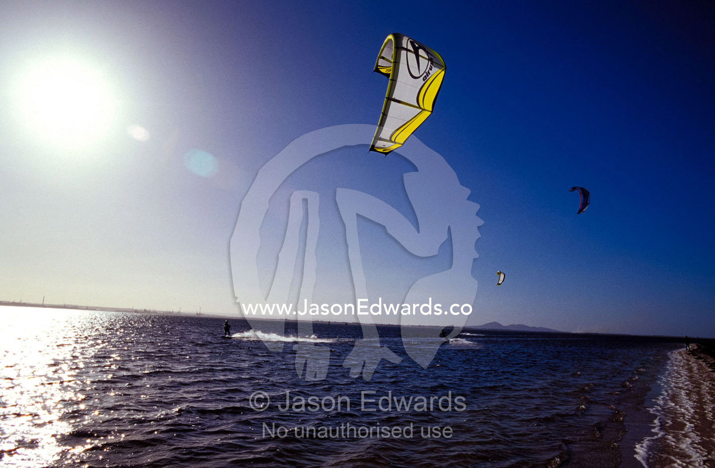 Three kite surfers on a windy summer day race across a bay. Point Henry, Victoria, Australia.