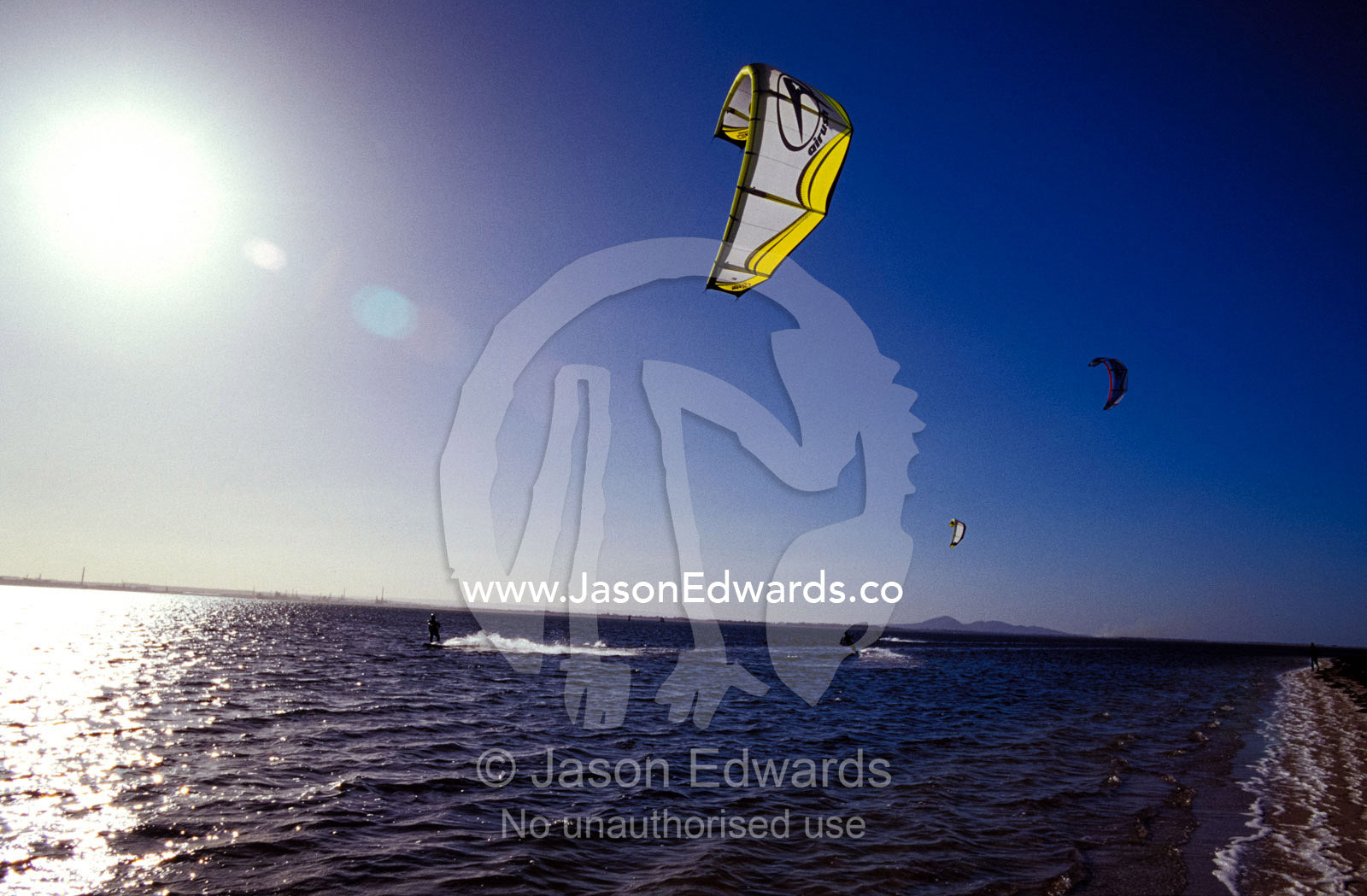 Three kite surfers on a windy summer day race across a bay. Point Henry, Victoria, Australia.