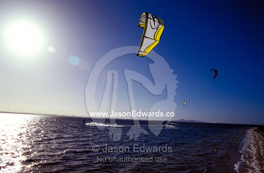 Three kite surfers on a windy summer day race across a bay. Point Henry, Victoria, Australia.
