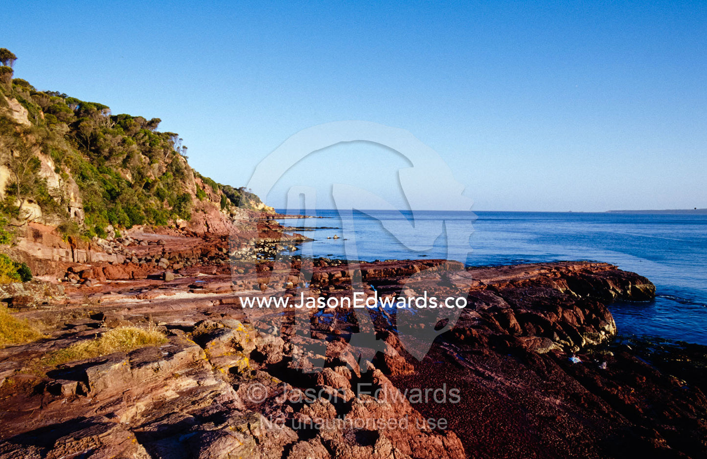 Rockpools in volcanic rock formations along a coastal cliff face. Merimbula Wharf, New South Wales, Australia.