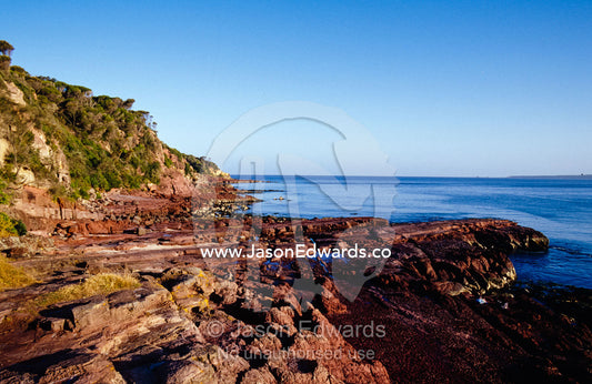 Rockpools in volcanic rock formations along a coastal cliff face. Merimbula Wharf, New South Wales, Australia.