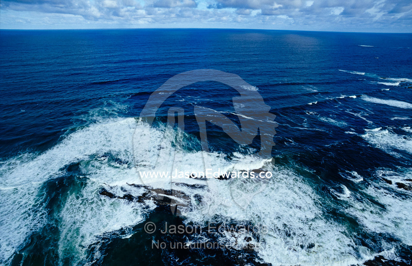 Waves smashing onto a rugged remote coastline beneath storm clouds. South West Conservation Area, Tasmania, Australia.
