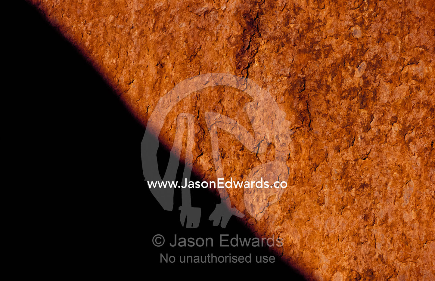 The red orange sandstone surface of Uluru, Ayres Rock, in shadow. Uluru, Kata Tjuta National Park, Northern Territory, Australia.