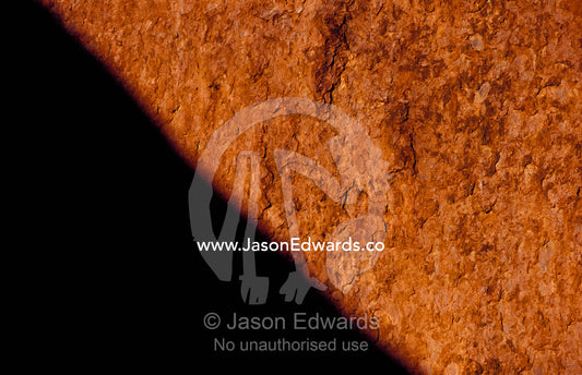 The red orange sandstone surface of Uluru, Ayres Rock, in shadow. Uluru, Kata Tjuta National Park, Northern Territory, Australia.