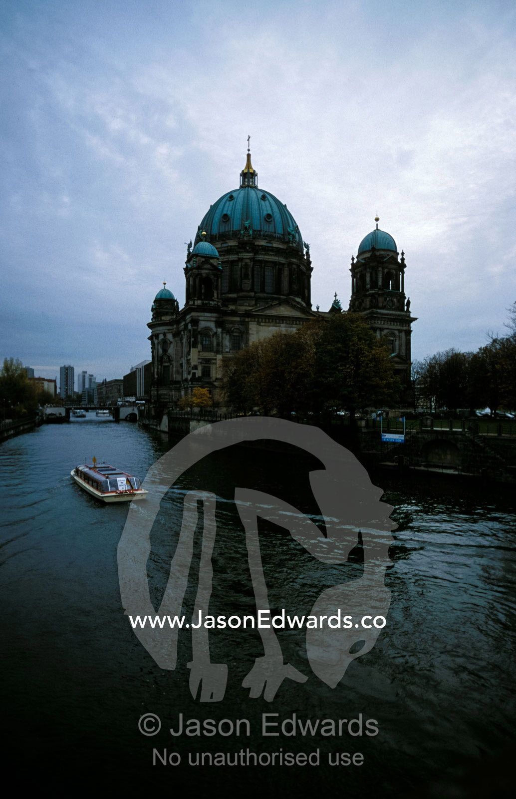 Berlin Cathedral and tourist boat on River Spree beneath storm clouds. Berlin, Brandenburg, Germany.