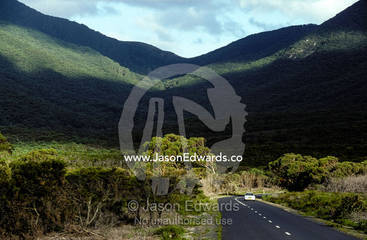 A lone vehicle meanders along a  picturespque coastal mountain road. Wilsons Promontory, National Park, Victoria, Australia
