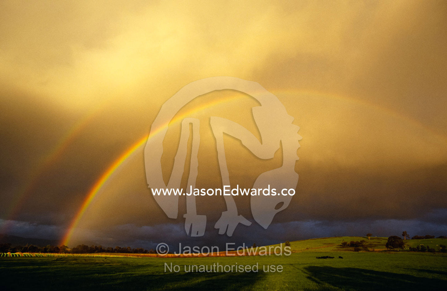 A spectacular double rainbow and storm clouds over farmland. Yarra Valley, Victoria, Australia.