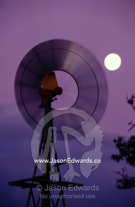 A rotating Windmill and a full moon in the purple sunset afterglow. Dunkeld, Victoria, Australia.