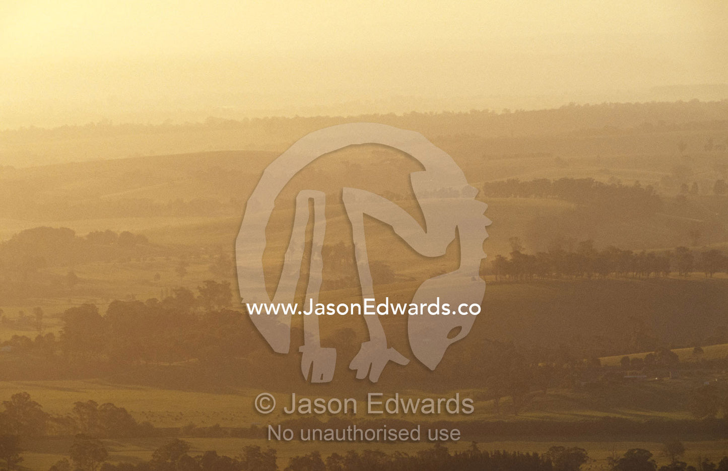 A hazy sunset over picturesque fields and rolling hills. Mt Raymond, Victoria, Australia.
